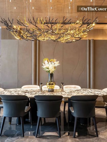 A nature-inspired chandelier serves as the stunning centerpiece of this dining area. The organic form of the light fixture contrasts beautifully with the clean lines of the furniture and wall paneling, creating a space that is both artistic and functional.