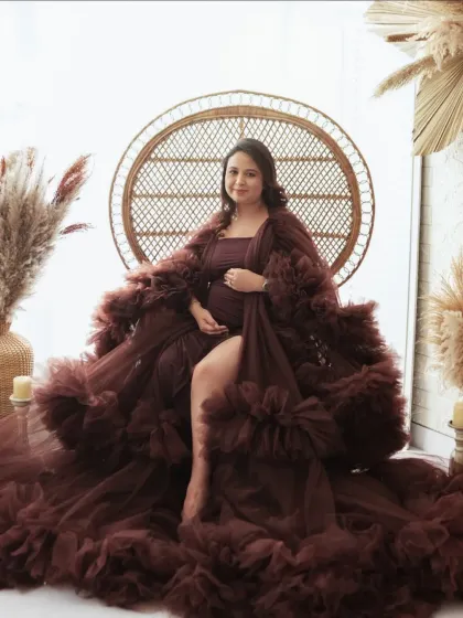 A stunning solo portrait of a mother-to-be. Seated in a peacock chair, she radiates confidence and joy in a beautiful ruffled gown, a perfect centerpiece for a maternity album.