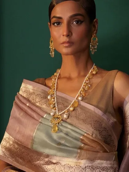 This campaign shot features a model in a beautiful pastel-toned saree, accessorized with a stunning pearl and citrine necklace, embodying timeless grace.