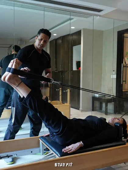 I believe in hands-on guidance. Here, I'm helping a client perfect her leg press form on the reformer, ensuring she engages the right muscles for maximum benefit and injury prevention.