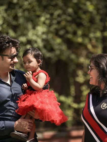 A candid shot of a family enjoying their time together outdoors, with the father holding their daughter.