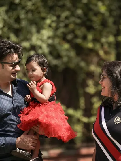 A candid shot of a family enjoying their time together outdoors, with the father holding their daughter.