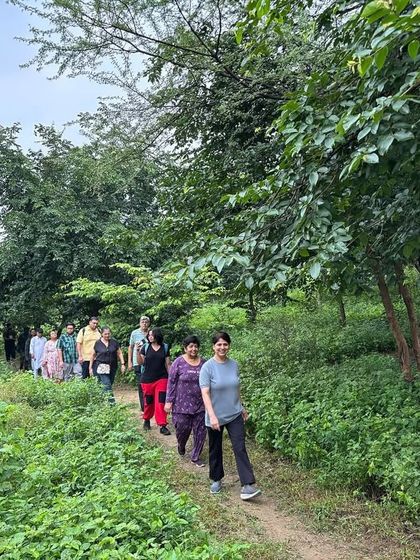 A group of citizens walks along a rustic trail at Ghata Bundh, surrounded by native trees, shrubs, and grasses that we have planted.