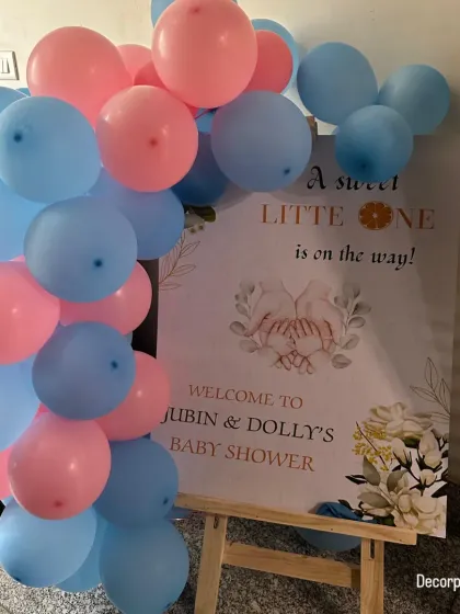 A sweet and simple welcome sign for a baby shower. The sign, which reads "A sweet little one is on the way," is adorned with a pink and blue balloon garland, perfectly setting the theme.