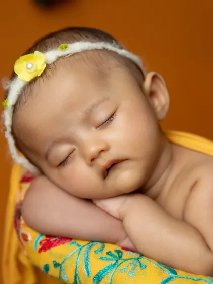 A close-up of a sleeping newborn's face, looking angelic during her mango-themed photoshoot.