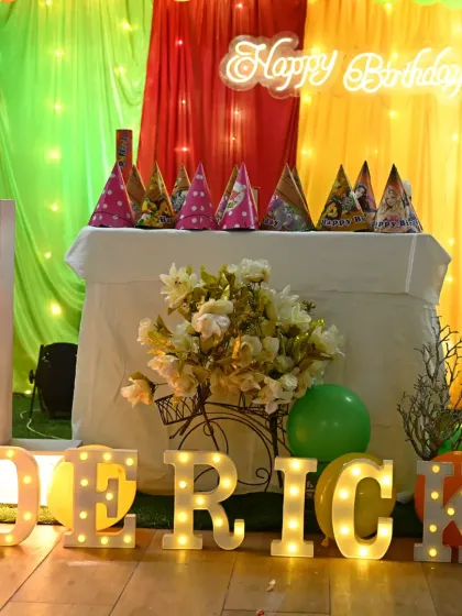 A close-up of the personalized decor for Derick's jungle-themed first birthday, including marquee letters and themed party hats.