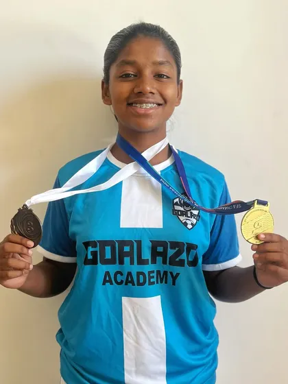 This player's dedication and hard work are paying off. She proudly displays her medals, a symbol of her many achievements with the academy.