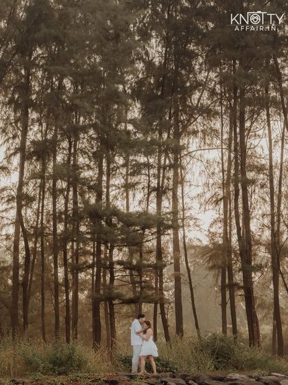 A dramatic wide shot of the couple dwarfed by towering trees. This composition creates a sense of awe and highlights the beauty of the natural landscape.