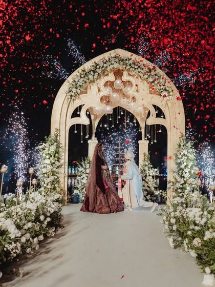 The climax of the varmala ceremony, set on a platform over the lagoon. A shower of red petals and a burst of cold pyrotechnics created a dramatic and unforgettable moment of celebration.