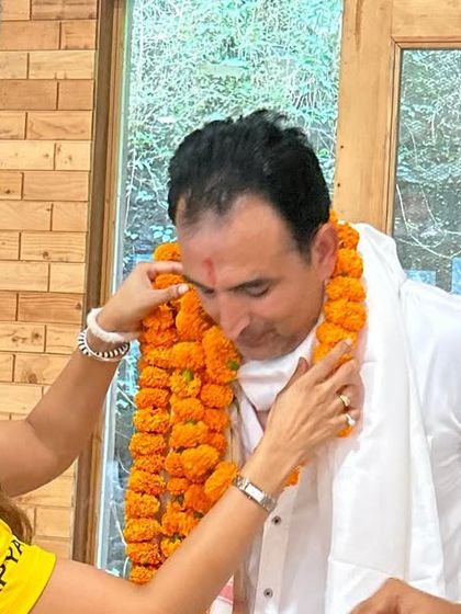 A student honors the guru with a traditional garland during the certification ceremony, a gesture of gratitude and respect.