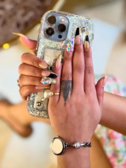 For those who dare to be bold, we create stunning 3D nail art. This dramatic look features long, sculpted extensions with a mix of glossy black, shimmering gold, and a statement nail covered in multifaceted crystals for maximum impact and sparkle.