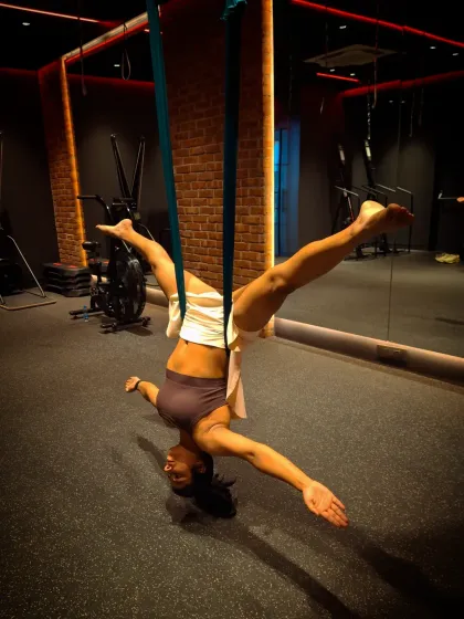 An inverted split pose in the aerial hammock. This move challenges your core stability and hip flexibility while building upper body strength to hold the position.