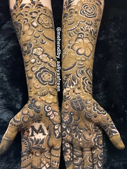 A stunning full-arm bridal design featuring a personalized initial 'M' on the palm.
