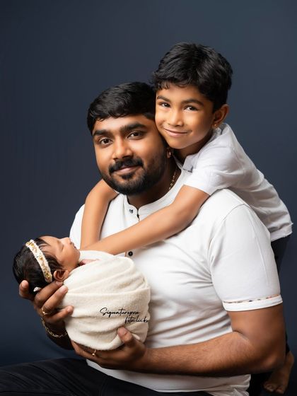 A father's strong and loving embrace, holding both his newborn and his proud older son. A beautiful portrait of fatherhood.