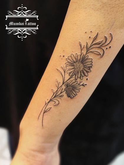 A beautiful floral tattoo of daisies on the forearm. The delicate shading and fine lines give these flowers a soft, natural look.