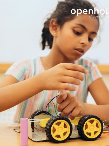 A young engineer meticulously works on her robotic car, connecting wires and learning about circuits. Our classes empower girls to dive into STEM with confidence.