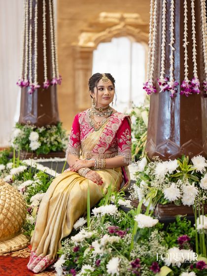 The client seated amidst beautiful floral decor, her traditional attire looking absolutely regal.