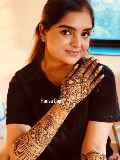 A beautiful bride showcasing her back-of-hand mehendi. The design is a mix of traditional motifs and modern symmetry, creating a look that is both elegant and timeless.