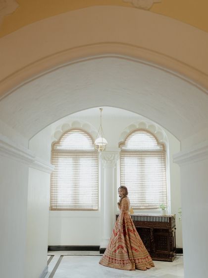 A simple, elegant portrait of the bride in a sunlit corridor. Her pose is natural and graceful, capturing a moment of quiet beauty.