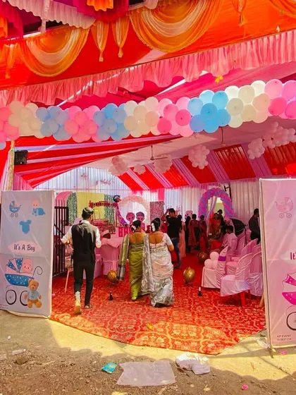 A wide view of a baby shower entrance under a large pandal, with a colorful balloon arch and welcome sign.