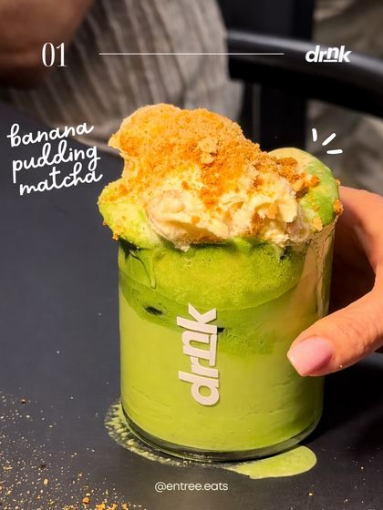 A close up on a Banana Pudding Matcha. The focus is on the decadent topping, making the drink look like a dessert in a glass. The lighting highlights the creamy texture, making it look incredibly tempting.