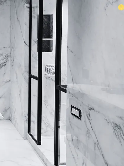 A detail from a bathroom in the 58WV project. The stark contrast between the black metal frame of the shower door and the heavily veined marble walls creates a bold, graphic statement.
