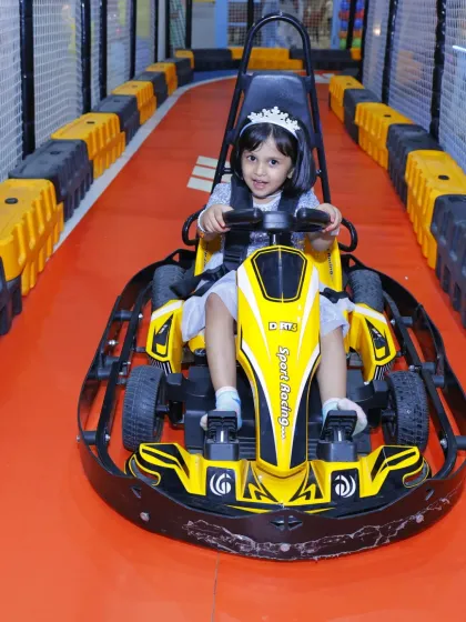 A little princess takes the wheel! Wearing a tiara, she's ready to rule the racetrack in her yellow go-kart.