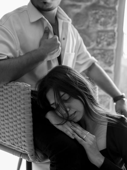 A moment of quiet contemplation in black and white. She rests her head, lost in thought, while he stands protectively by her side.