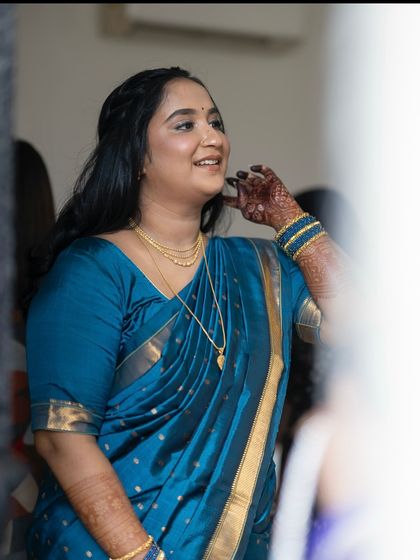 A candid shot from a traditional ceremony. The makeup is natural and subtle, allowing the client's happy expression to be the focus.
