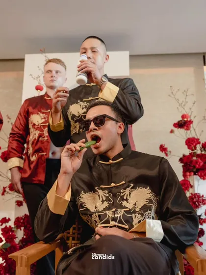 The groom and his friends endure the "spice test," eating bitter melon and chillies to prove his love. This candid shot captures the fun and determination involved in this Chinese wedding tradition.