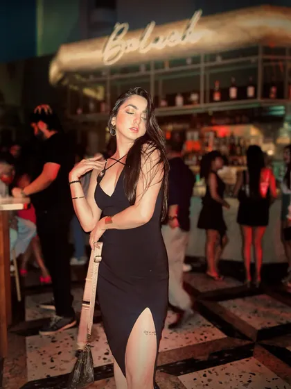 A candid shot in a black dress, capturing the motion and energy of a crowded bar.