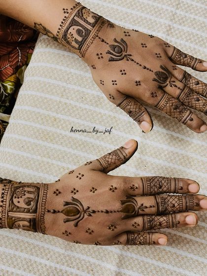 A semi bridal design featuring lotus motifs and elephant figures in boxes on the wristband. The pattern is lighter, with spaced out elements on the palm and fingers.