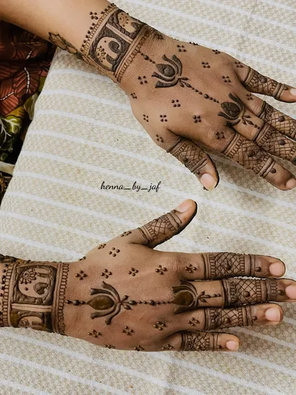 A semi bridal design featuring lotus motifs and elephant figures in boxes on the wristband. The pattern is lighter, with spaced out elements on the palm and fingers.