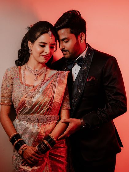 A warm and intimate reception portrait using red-toned lighting. The couple's close embrace and gentle expressions create a deeply romantic photograph.