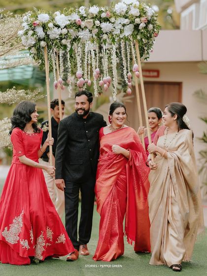 The bride, Jesna, making her entrance under a beautiful floral canopy held by her bridesmaids. This is a unique and lovely way to capture the bridal procession.