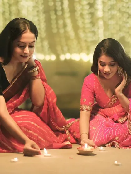 Two friends lighting diyas together on the ghats of Varanasi. A heartwarming image that embodies the spirit of celebration and togetherness during Dev Deepawali.