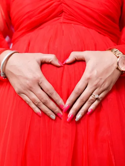 A close up shot focusing on the heart of the matter. Making a heart shape with your hands on your belly is a classic and sweet pose that symbolizes all the love you have for your baby.