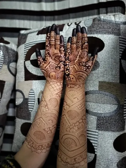 Freshly applied bridal henna with bold, dark fingertips. The contrast between the fine lines and the fully covered tips is a classic element of bridal mehndi.