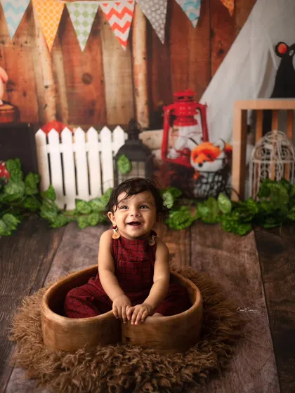 Bright eyes and chubby cheeks are always a winning combo. This little guy's happy smile is just infectious in this rustic woodland setup.