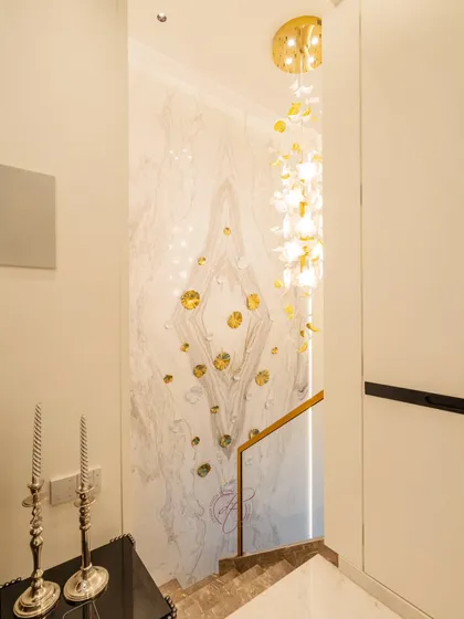 Looking down the staircase, this shot highlights the intricate 3D floral embellishments on the marble feature wall. These details add a bespoke, artistic touch to the home.