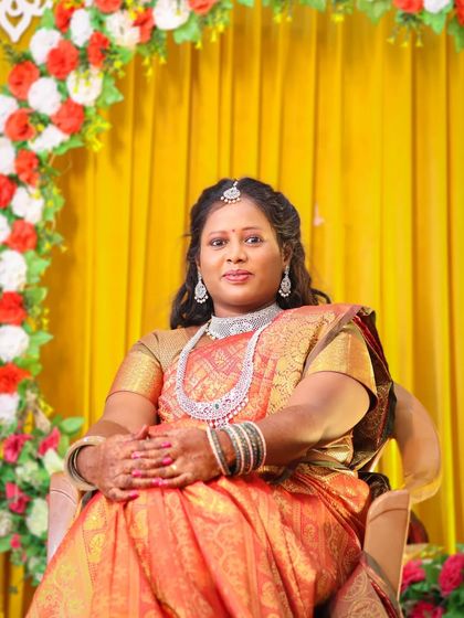 A direct and confident portrait of the bride. She is looking straight at the camera, showcasing her beautiful makeup and traditional attire against the festive wedding backdrop.