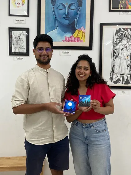 A couple with their miniature canvas paintings. The smiles say it all. It's about the shared experience as much as the art itself.