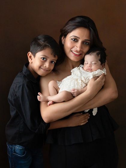 A mother holds her newborn daughter while her son stands proudly beside them. This portrait, shown in both color and black and white, captures the warmth of a growing family.