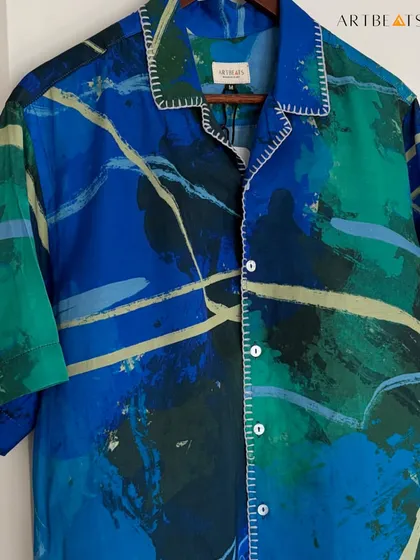 A close-up of the Komorebi shirt, showing the hand-stitched details along the collar and placket, which add a layer of craftsmanship to the vibrant, painterly print.