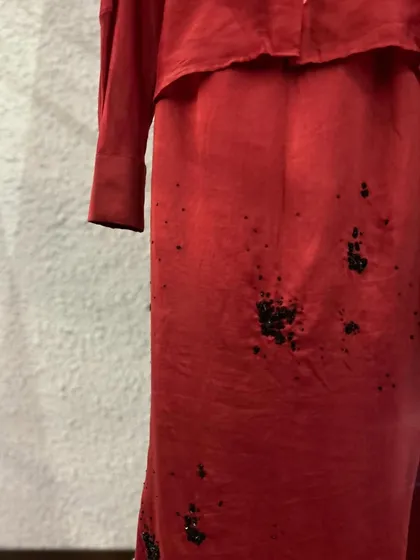 A close-up of the red co-ord set, highlighting the artistic black splatter embroidery on the skirt.