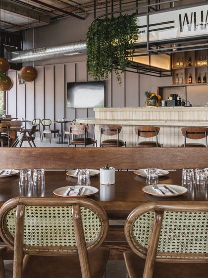 The high ceilings and open layout allow the restaurant to seat up to 120 people without feeling crowded. The community table in the foreground is perfect for large parties or encouraging social interaction.