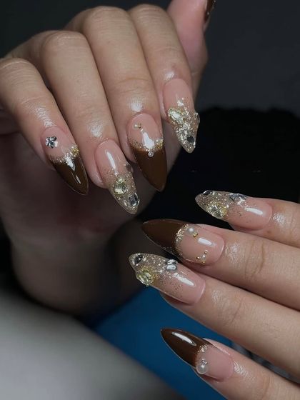 A bold look combining rich brown polish with heavily embellished accent nails. Learning to balance solid colors with complex gem work is a key skill.