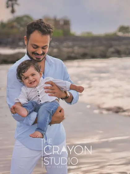 A father cradles his laughing son in his arms by the sea. This portrait is full of warmth and paternal affection, a perfect memory from a day spent at the beach.