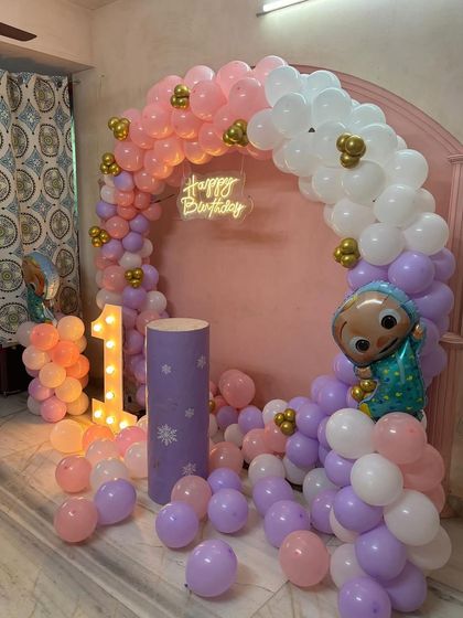 This shot of the pastel Cocomelon party focuses on the character foil balloon and the light-up number '1'.