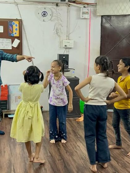 An instructor playfully directs the Primary School Choir, their smiles showing how much fun they are having while learning musical concepts.